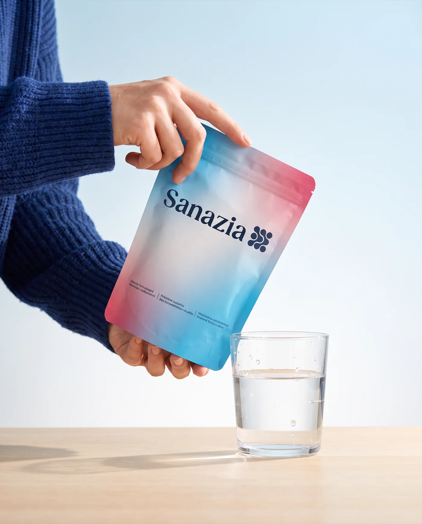 Hands holding a Sanazia pack over a glass of water
